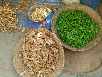 High angle view of gingers and green chili peppers for sale in baskets at market