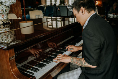 Man sitting while playing grand piano