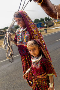 Mother and daughter with camel walking on road