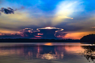 Scenic view of lake against dramatic sky during sunset