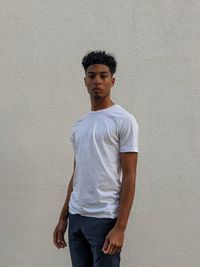 Portrait of young man standing against wall