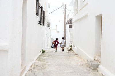 Rear view of people walking on alley amidst buildings