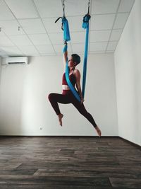 Low angle view of woman hanging on textile while exercising at home