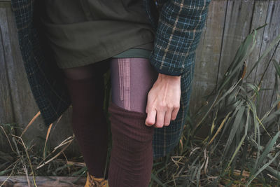 A woman straightens her stocking outdoors on a cold autumn day.