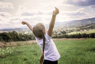 Rear view of boy with arms raised on field