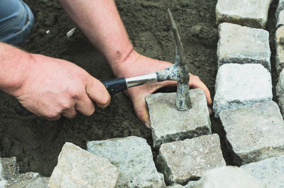 A paver cobbles porphyry stones into the concrete. the hammer lies on the stone