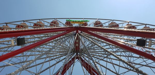 Low angle view of ferris wheel against clear blue sky