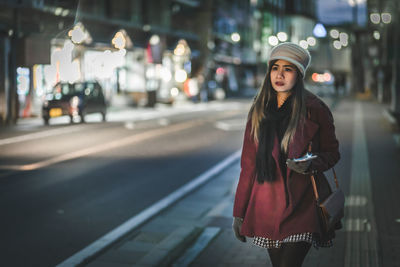 Young woman standing on road in city