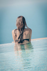 Rear view of woman in swimming pool against sea