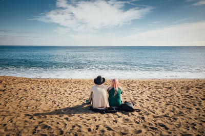 Rear view of women sitting on beach