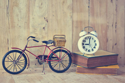 Close-up of toy bicycle with alarm clock and books on table