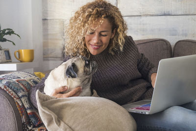 Smiling woman sitting with dog at home