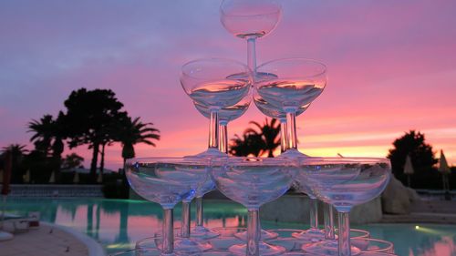 Stack of martini glass on table against sky during sunset