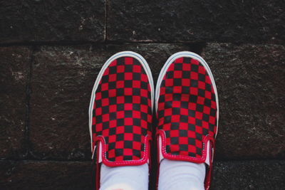 Low section of person standing by red shoes