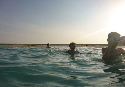 People enjoying in sea against sky