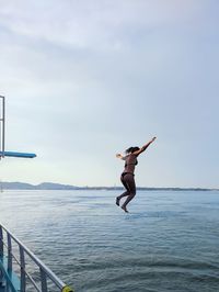 Man jumping in sea against sky