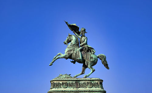 Low angle view of angel statue against clear blue sky