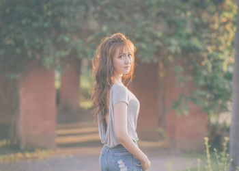 Side view portrait of beautiful young woman standing on footpath