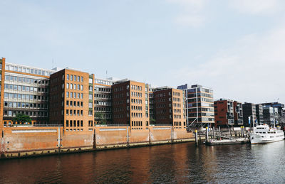 Buildings by river against sky in city