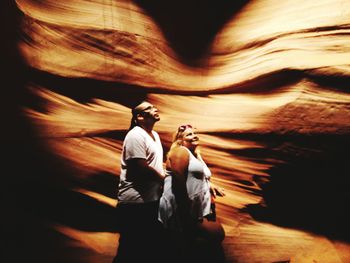 Side view of man and woman walking by rock formations
