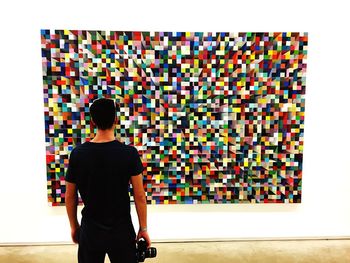 Rear view of woman standing against multi colored wall