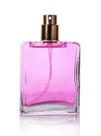 Close-up of glass of pink bottle against white background