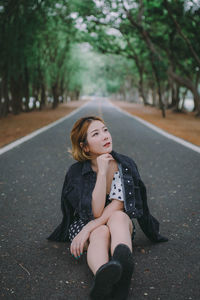 Woman looking away while sitting on road