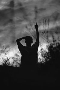 Rear view of silhouette man standing in park against sky