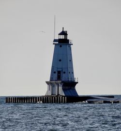 Lighthouse by sea against clear sky
