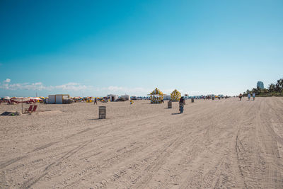 People on beach against clear blue sky