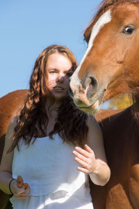 Low angle view of young woman with horse standing against clear sky