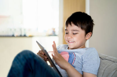 Boy looking away while sitting on laptop