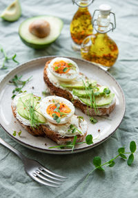 Bread toast, boiled eggs, avocado slice, microgreens on a plate, breakfast time