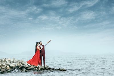 Woman standing by sea against sky