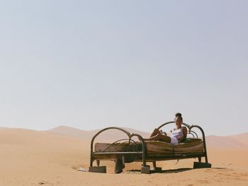 Woman lying on old bed in desert