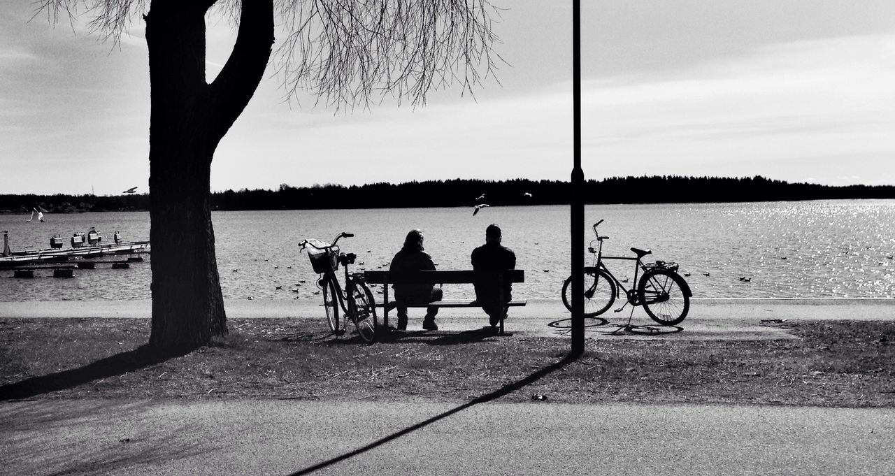 bicycle, men, transportation, lifestyles, mode of transport, leisure activity, silhouette, water, sky, togetherness, riding, land vehicle, person, full length, sea, beach, sitting