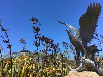 Bird statue against blue sky