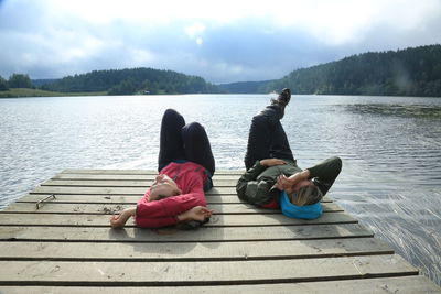 Couple sitting on pier at lake