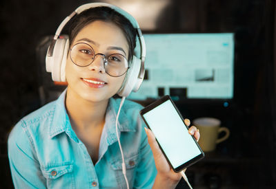 Portrait of smiling woman holding mobile phone