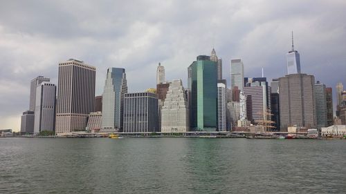 Sea by modern buildings against sky in city