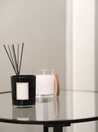 Scented candles and aroma diffuser with sticks, trendy glass bedside table. modern interior details