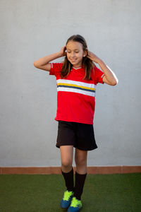 Smiling girl standing against wall