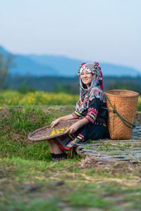 Woman sitting on wicker basket on field