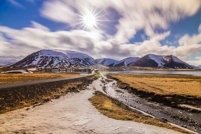 Road amidst snowcapped mountains against sky