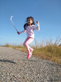 Girl levitating on road against blue sky