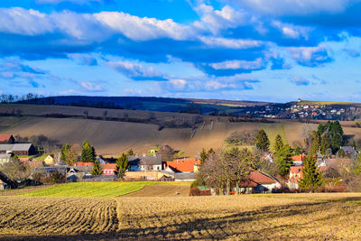 Scenic view of agricultural field by houses against sky