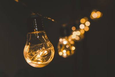 Close-up of illuminated light bulb against black background