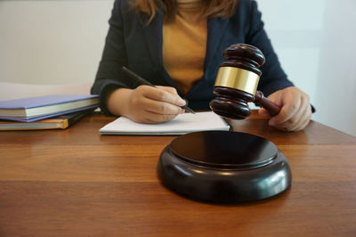 Midsection of woman reading book on table