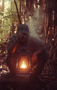Man smoking vape holding an oil lamp in the forest