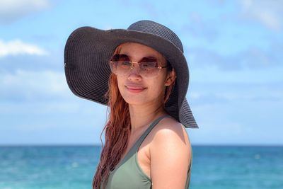 Portrait of young woman wearing hat standing at beach